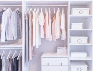 clothes hanging on rail in white wardrobe with boxes